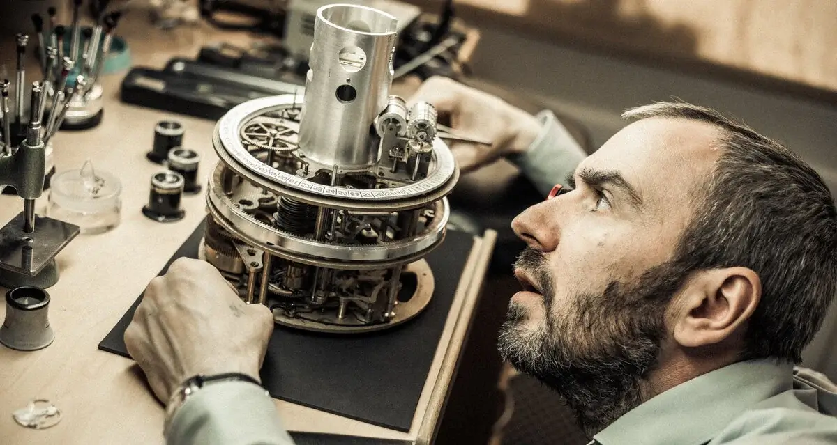 An artisan's hands carefully assembling a clock.