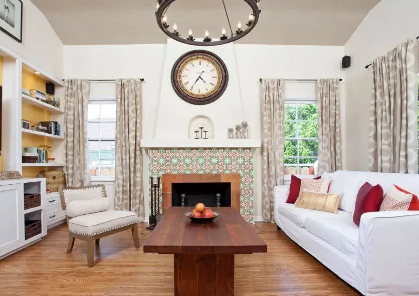 A sleek metal clock in a modern kitchen with stainless steel appliances.